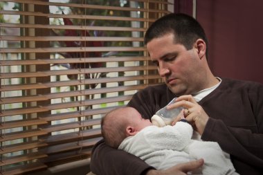 Babası onun bebek şişe beslenir.