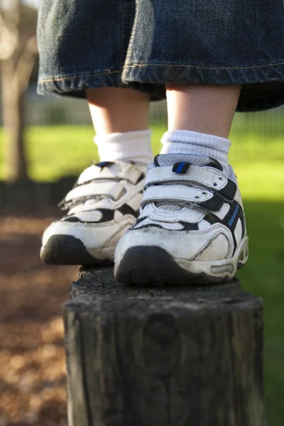 Los zapatos de un niño parado en un poste — Foto de Stock