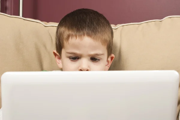 Menino se concentra ao usar um computador netbook branco — Fotografia de Stock