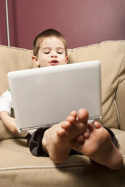 Niño trabaja en una computadora Netbook —  Fotos de Stock