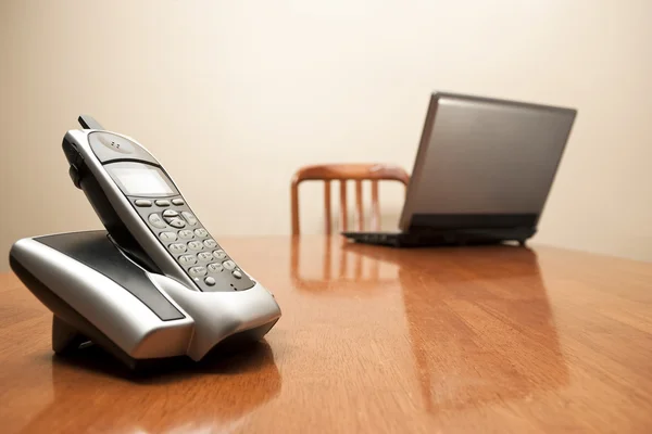 Telefone sem fio e laptop na mesa — Fotografia de Stock