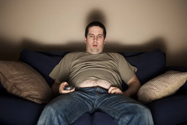 Overgewicht slob kijken tv Stockafbeelding