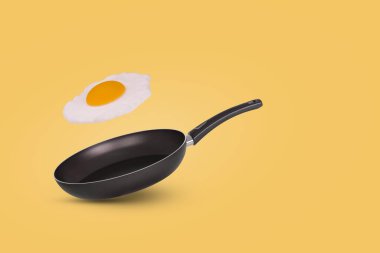 Küçük bir tava ve sarı arka planda uçan bir yumurta fikri. Yaratıcı gıda konsepti. Reklam, web, menü, restoran için uygun.