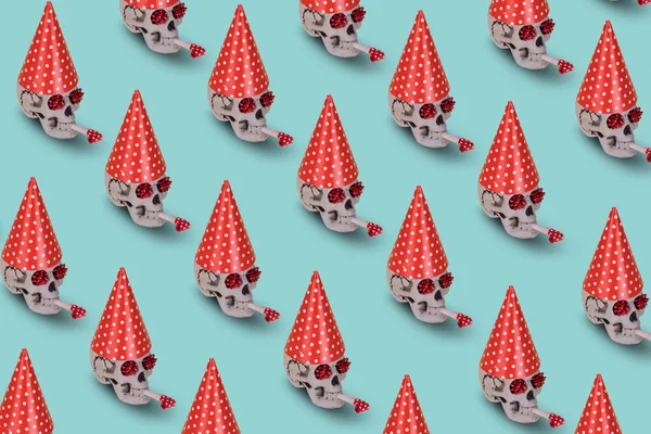 Pattern of human skull  with a red birthday cap and whistle on a blue background. Minimal holiday celebration funny concept. Halloween creative background.