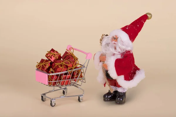 最小限のクリスマスセール組成 サンタ条項とベージュの背景に飛んで贈り物とショッピングカートやトロリー 幸せな休日 新年のミニマルなコンセプト — ストック写真