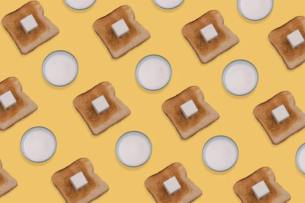 图样由烤面包 黄油和一杯牛奶在黄色背景下制成 最小和创造性的早餐概念 顶部视图 当代平铺 — 图库照片