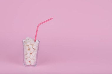Pastel pembe arka planda kamışla dolu bir bardak şeker. Sağlıksız diyet konsepti. Asgari fikir, alanı kopyala.