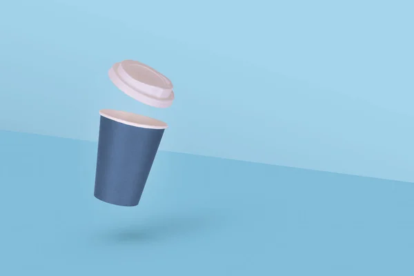 一个一次性纸制咖啡杯 白色的帽子在空气中飘扬 蓝色背景隔离 最小外卖概念 复制空间 — 图库照片