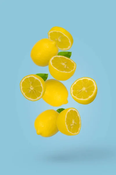 ジューシーな熟した全体と薄い青の背景に飛んでスライスされたレモン 創造的な食品コンセプト 熱帯有機果物 柑橘類 ビタミンC最小限の夏の果物の背景 — ストック写真