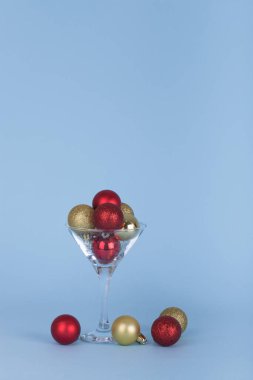 Kokteyl ya da martini bardağı ve mavi arka planda noel süsleri. Asgari Noel partisi fikri. Yaratıcı Xmas veya Yeni Yıl Kutlama Konsepti.