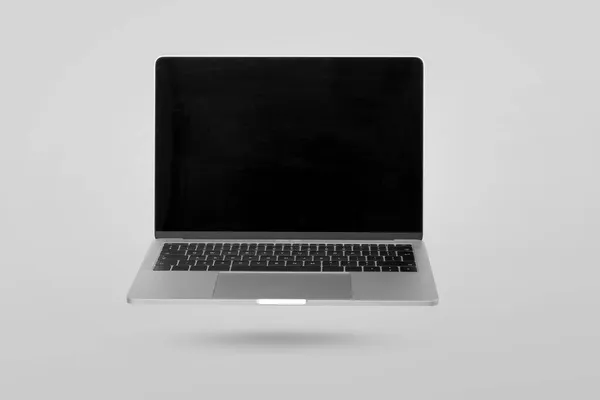 Laptop Mit Leerem Bildschirm Der Der Luft Vor Grauem Hintergrund — Stockfoto