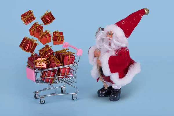 最小限のクリスマスセール組成 青い背景に箱の中でギフトを飛んでサンタ条項とショッピングカートやトロリー 幸せな休日 新年のミニマルなコンセプト — ストック写真