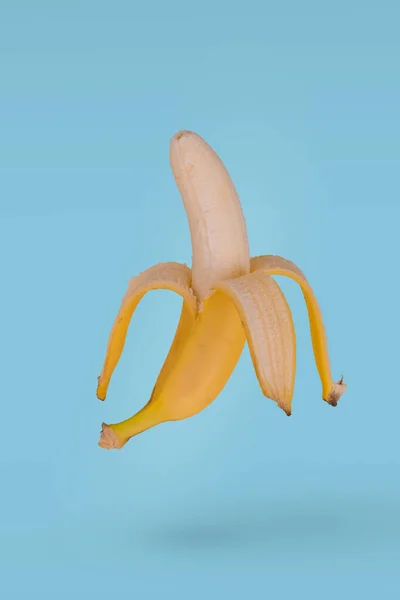 Mezza Banana Matura Pelata Che Vola Aria Isolata Sfondo Blu — Foto Stock