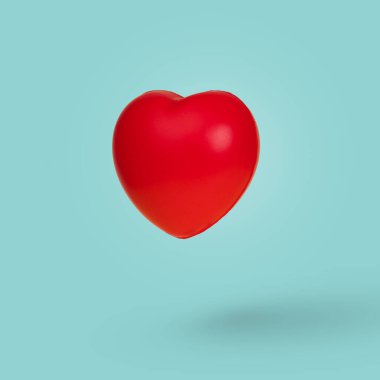 Pastel mavi arka planda havada kırmızı yüzen bir kalple yaratıcı bir fikir. Mutlu Kadınlar, Anneler Günü, Sevgililer Günü, doğum günü tebrik kartı tasarımı için asgari sevgi sembolü
