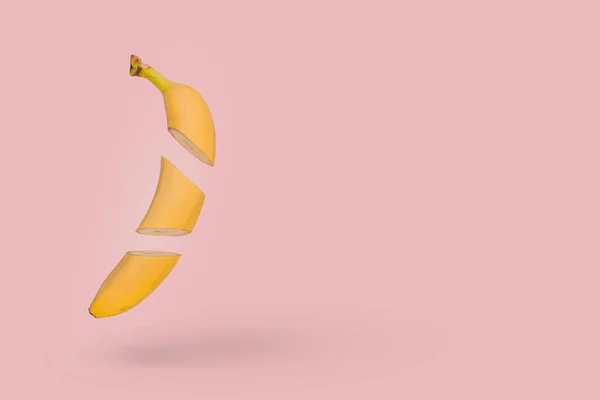 新鲜的切碎香蕉漂浮在空气中 隔离在粉红的背景上 最小的水果概念 复制空间 图库图片