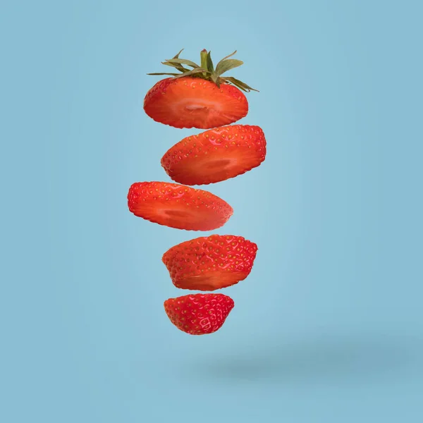 Creatieve Compositie Met Gesneden Aardbeien Vliegen Lucht Geïsoleerd Een Helderblauwe — Stockfoto
