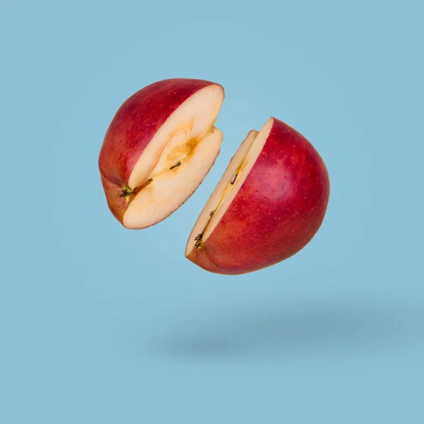 两半浮动的成熟苹果在明亮的蓝色背景 维生素 健康饮食的概念 最小的水果的想法 切碎的苹果漂浮在空中 有飞果的创意概念 — 图库照片