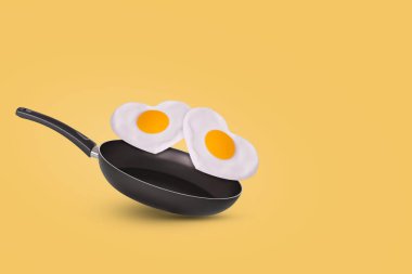 Kızartma tavası ve sarı arka planda kalp şeklinde kızarmış yumurta ile yaratıcı bir fikir. En az yemek ve aşk konsepti. Sevgililer Günü için kahvaltı fikri ve romantik bir sabah. Boşluğu kopyala.