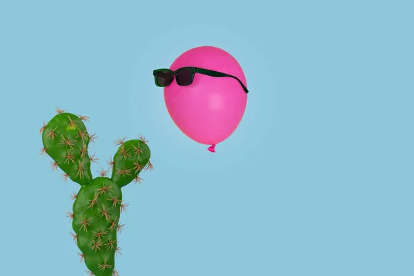仙人掌植物 上面有一个粉色气球 戴着太阳镜 与明亮的蓝色背景隔离 创意最小的概念 用于卡片 横幅和网页设计 复制空间 — 图库照片