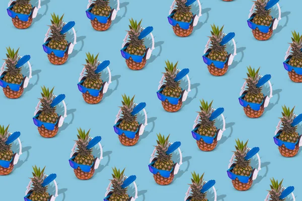 Creative trendy summer pattern with pineapple wearing sunglasses and headphones on bright blue background. Creative scene of fun, party, fashion, trend and funny art design.