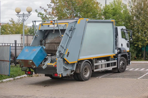 Çöp toplama servisi çöp toplamak için çöp tenekelerini boşaltmaya çalışan bir çöp toplayıcı bir kamyon ve çöp tenekesi, geri dönüşüm konsepti..