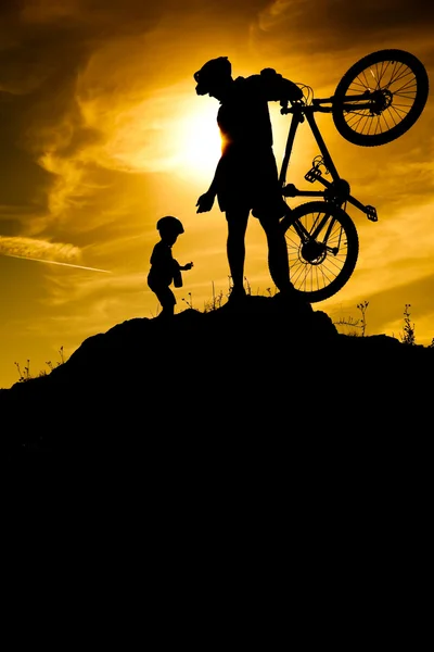 Silueta de ciclista de montaña al amanecer. Papá con hijo —  Fotos de Stock