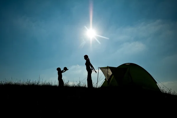 Familie camping. silhouet van moeder en zoon plezier buiten in de buurt van tent. herfst zomer outdoor activiteit concept. toerisme concept — Stockfoto