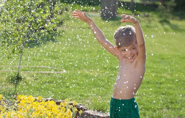 Portret ładny dziecko grając w ogrodzie w deszczu w ruchu — Zdjęcie stockowe