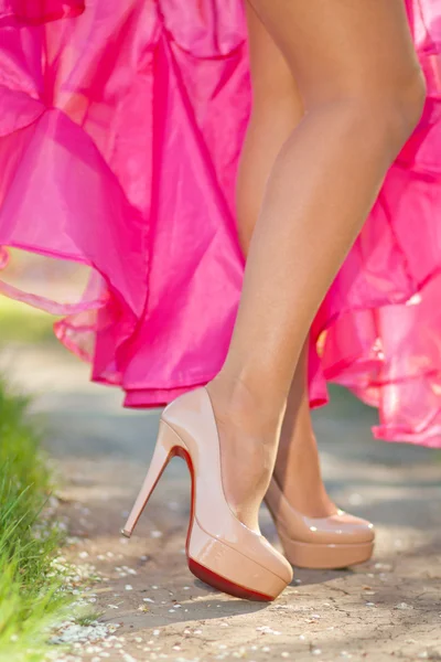 Patas femeninas delgadas en zapatos de tacón alto al aire libre. luz solar — Foto de Stock