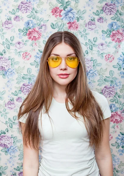 Cute summer woman wearing trendy yellow glasses over flower background — Stock Photo, Image