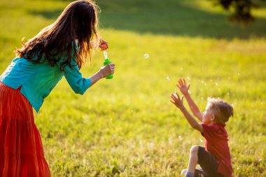 mutlu bir aile açık havada yaz Park'ta eğleniyor. arkadan aydınlatmalı. Anne üzerinde odaklanmak