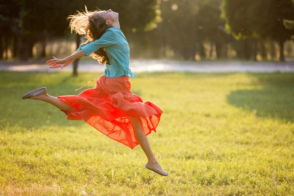 Junge Frau springt im Park in Bewegung. weiches Gegenlicht — Stockfoto