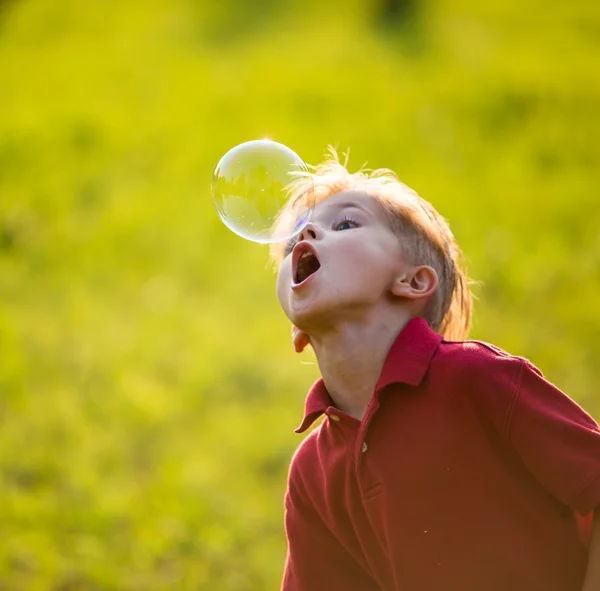 Boy having fun playing with soap bubbles. focus on bubble — Stock Photo, Image