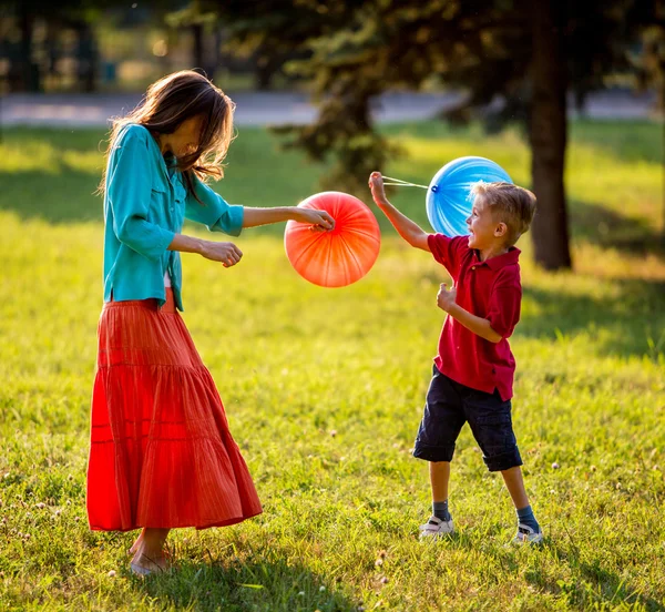 Mother and son having fun in the spring park in motion. backlit. focus on mother — Stock Photo, Image