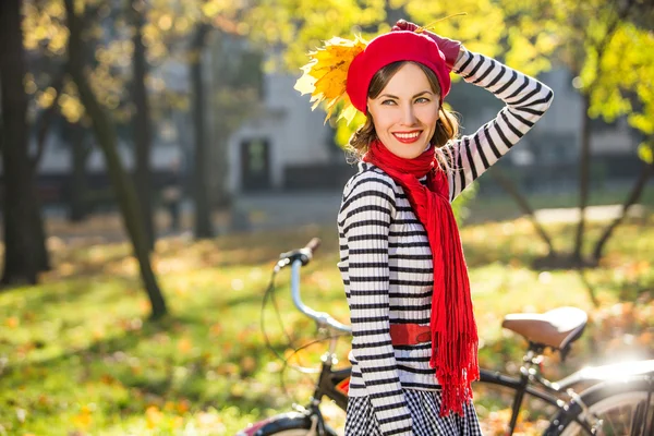 Carefree adorable young woman in autumn park holding autumn leaves and looking to the side. copy space — Stock Photo, Image