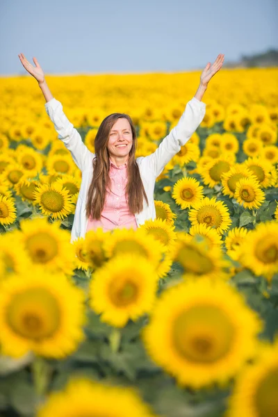 Krásná žena v slunečnicová pole s outstreched rukama — Stock fotografie