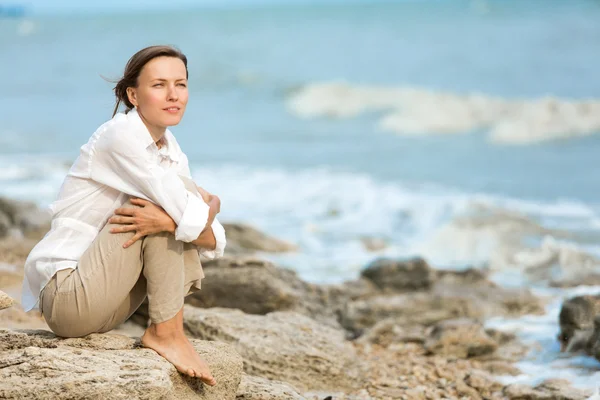 Donna felice in vacanza godendo sulla spiaggia rocciosa, donna che medita al mare — Foto Stock