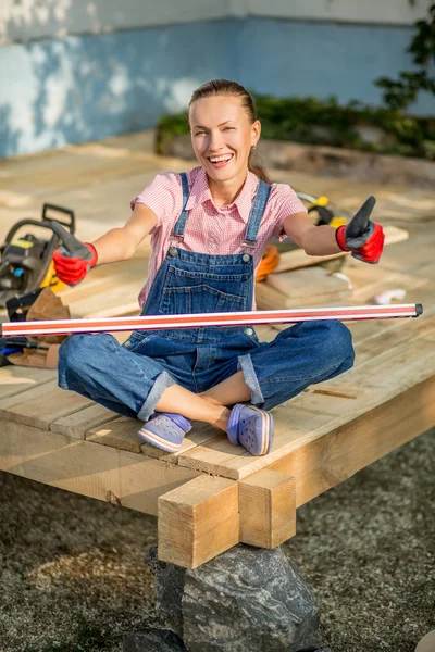 Attractive smiling builder woman with tools showing thumbs up — Stock Photo, Image