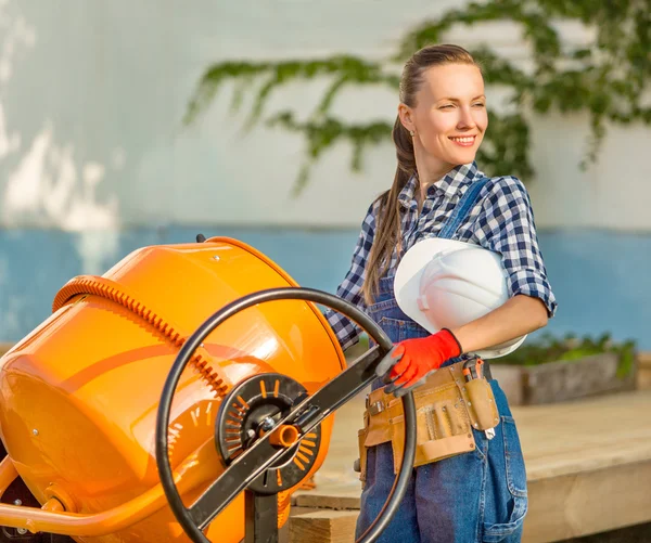 Pretty young woman builder and concrete mixer — Stock Photo, Image