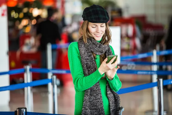 O tânără pasageră de la aeroport folosind telefonul ei inteligent — Fotografie, imagine de stoc