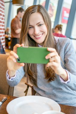 bir kafede otururken cep telefonu kullanan kadın