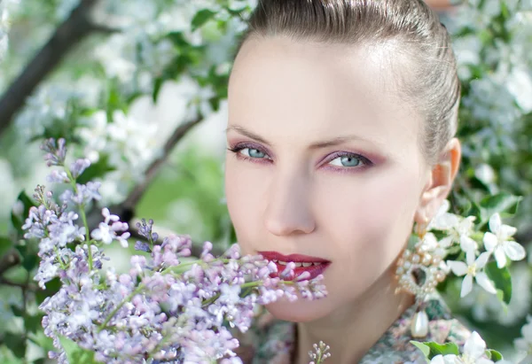 Schöne Frau mit lila Blüten — Stockfoto