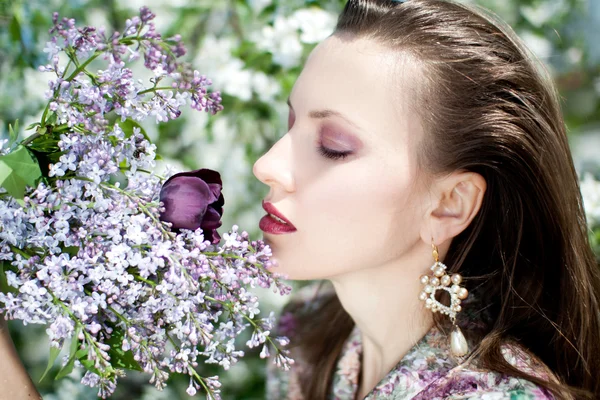Mujer joven con flores lila — Foto de Stock