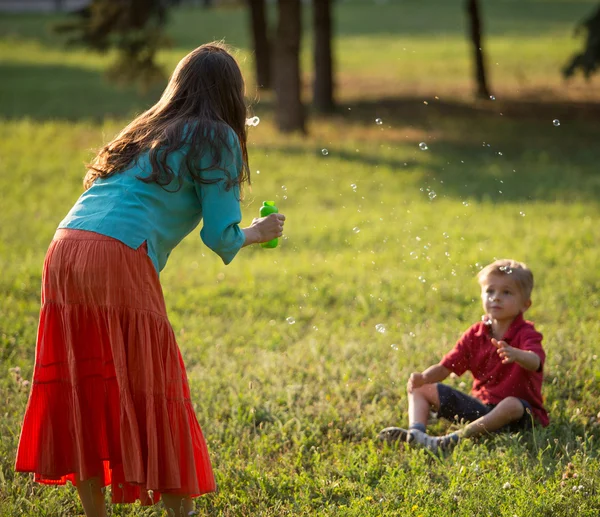 Felice famiglia soffia bolle nel parco — Foto Stock