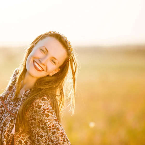 Mooie lachende vrouw in een veld bij zonsondergang — Stockfoto