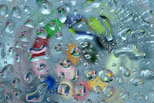 Gota de agua colorida sobre fondo de vidrio — Foto de Stock