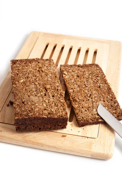 Dark rye bread whith knife on a board — Stock Photo, Image