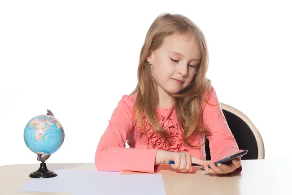 Little girl sits at a table with phone and draws — Stock Photo, Image
