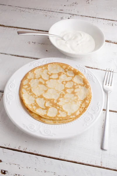 Panqueques caseros panqueques en un plato con crema agria en madera ta — Foto de Stock