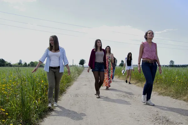 Group of young women walking on a field of wildflowers — Stock Photo, Image